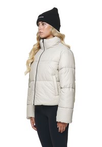 Beige Daunenjacke mit hohem Kragen, frontalem Reißverschluss und Seitentaschen. Hat eine glänzende Struktur und das Markenlogo auf der Brust.