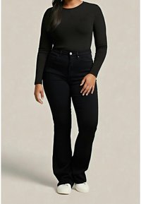 Jean noir taille haute à coupe droite, associé à un top noir ajusté à manches longues et des chaussures blanches. Texture de tissu lisse.