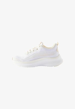 Witte sportieve schoen met een gestructureerde gebreide bovenkant, ronde neus en dikke witte zool; heeft veters en een lipje aan de hiel.