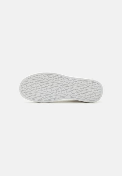 Semelle de basket blanche avec un motif répétitif "DD" et étoiles sur un fond clair uni.