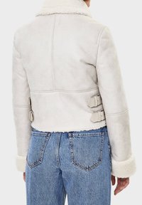 Kurtka z imitacji owczej skóry w jasnoszarym kolorze o teksturowanym wykończeniu, z szerokim kołnierzem, bocznymi klamrami oraz kontrastowymi mankietami z owczej skóry.