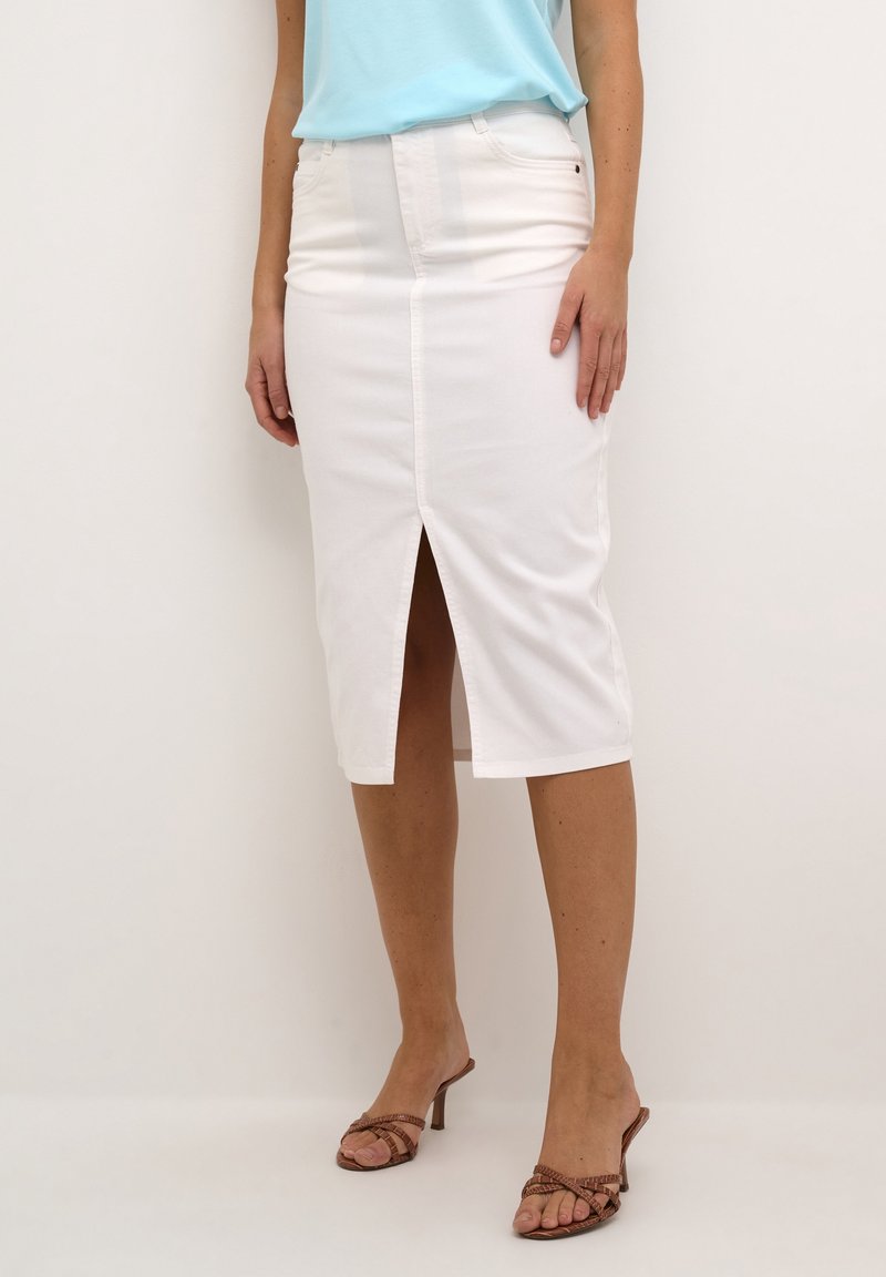 Gonna midi in denim bianco con spacco frontale, forma strutturata e tasche. Abbinata a un top azzurro chiaro e sandali con tacco color cuoio.