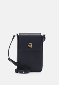 Monedero cruzado en color azul marino fabricado en piel sintética, con cierre de solapa, detalles en logo dorado, correa desmontable y textura suave.