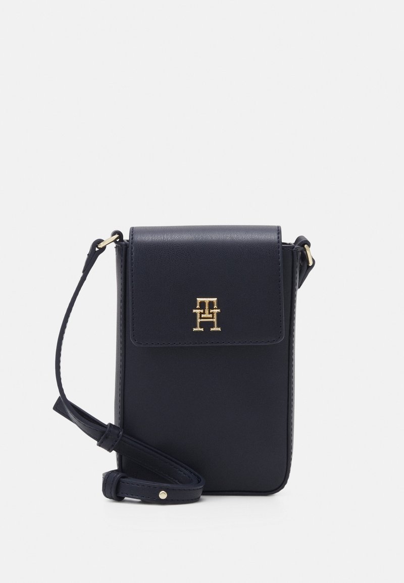 Monedero cruzado en color azul marino fabricado en piel sintética, con cierre de solapa, detalles en logo dorado, correa desmontable y textura suave.