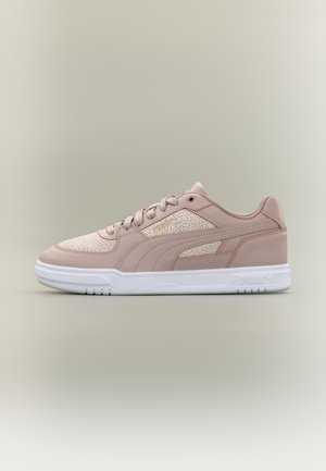 Beige lage sneaker met wit gevlekt paneel, beige veters en een witte zool met Puma-logo aan de zijkant en hiel.