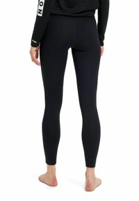 Leggings neri aderenti realizzati in tessuto elasticizzato, con una texture liscia e cuciture minime, progettati per il comfort e la mobilità.