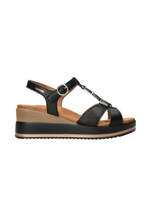 Sandale compensée noire avec dessus en cuir, bride réglable, accent argenté et plateforme texturée. Doublure intérieure marron et semelle en caoutchouc.