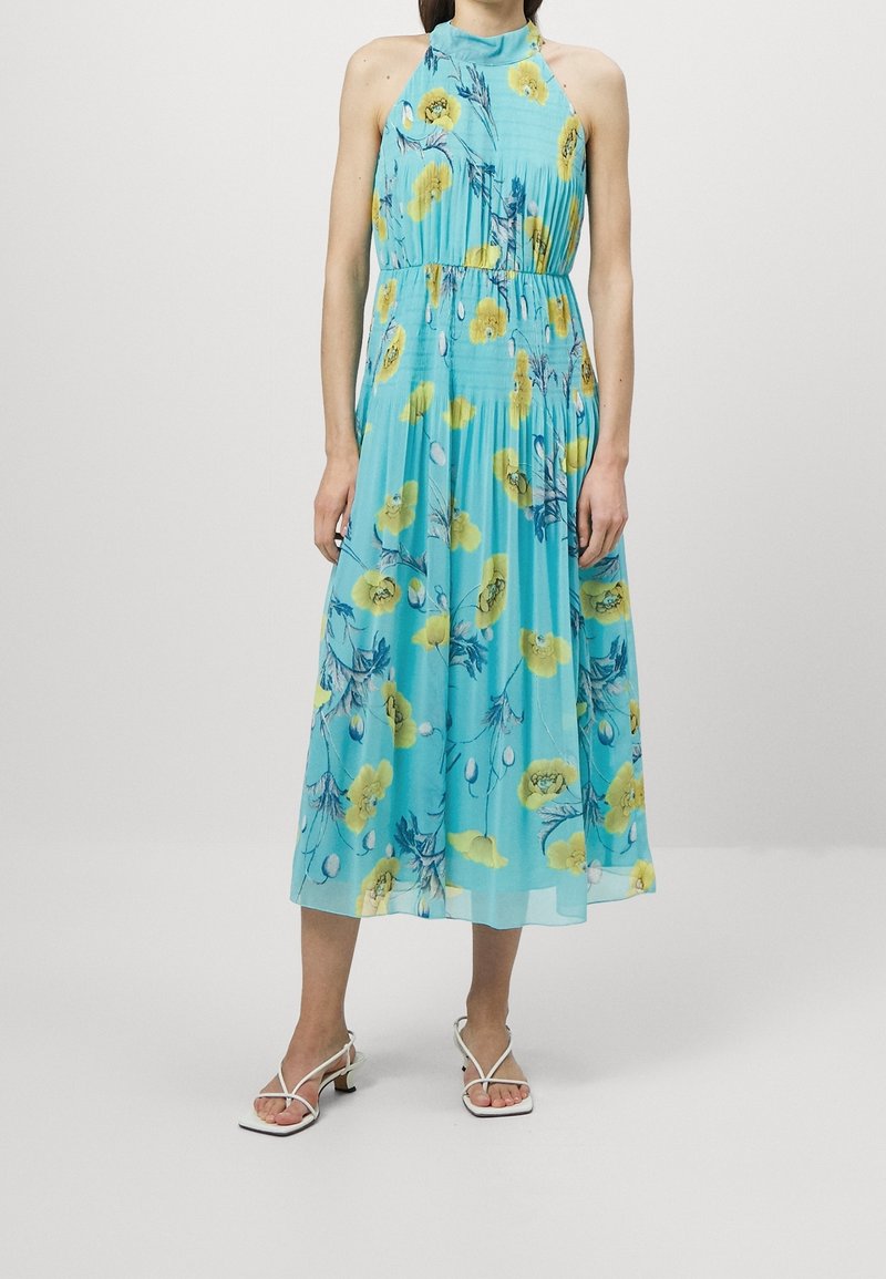 En ljusblå halterneck-klänning med ett blomstermönster i gult och grönt. Den har en figurnära midja och en flödande midiklänning.