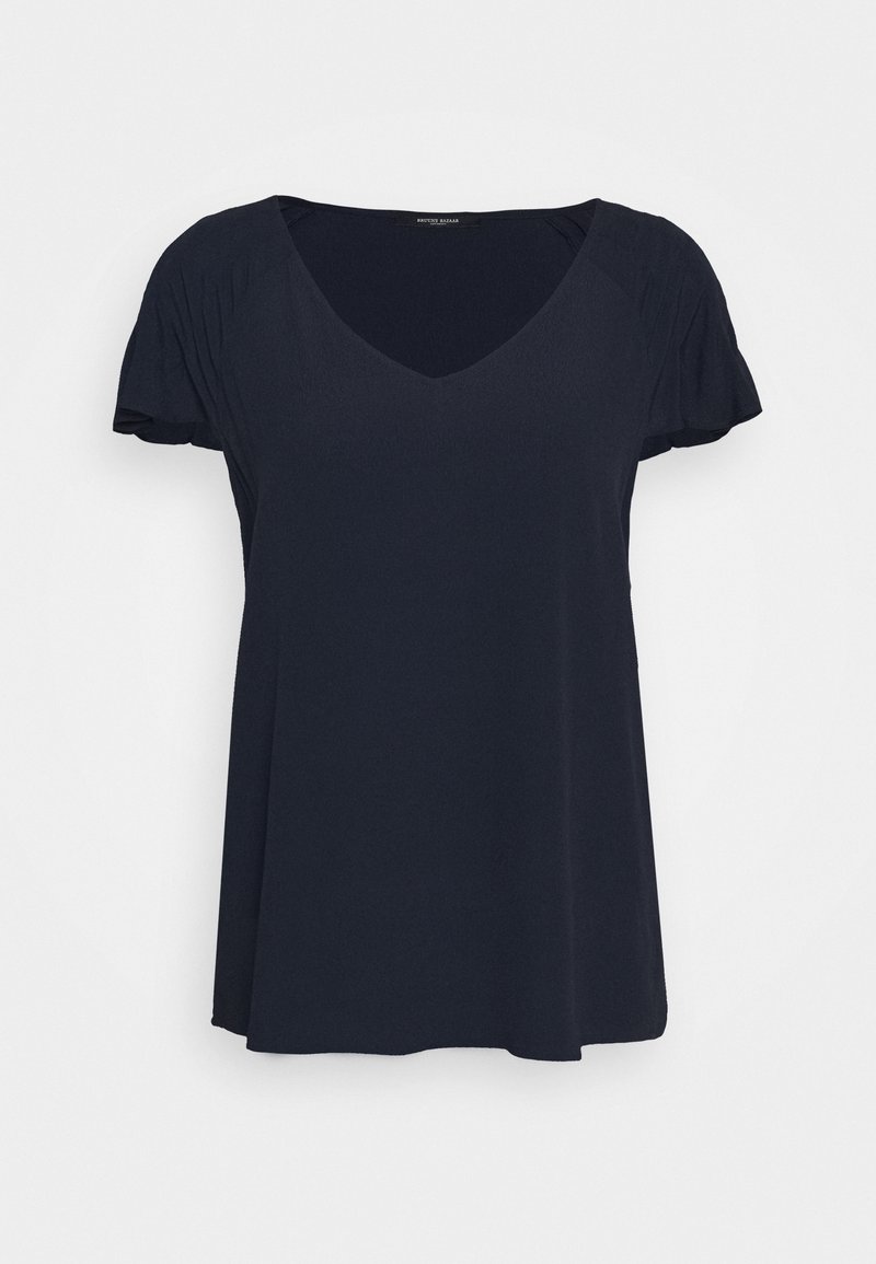 Námořnická modrá krátká rukávová halenka s výstřihem do V, vyrobená z měkké tkaniny a s nařasenými detaily na ramenou. Uvolněný, splývavý střih.