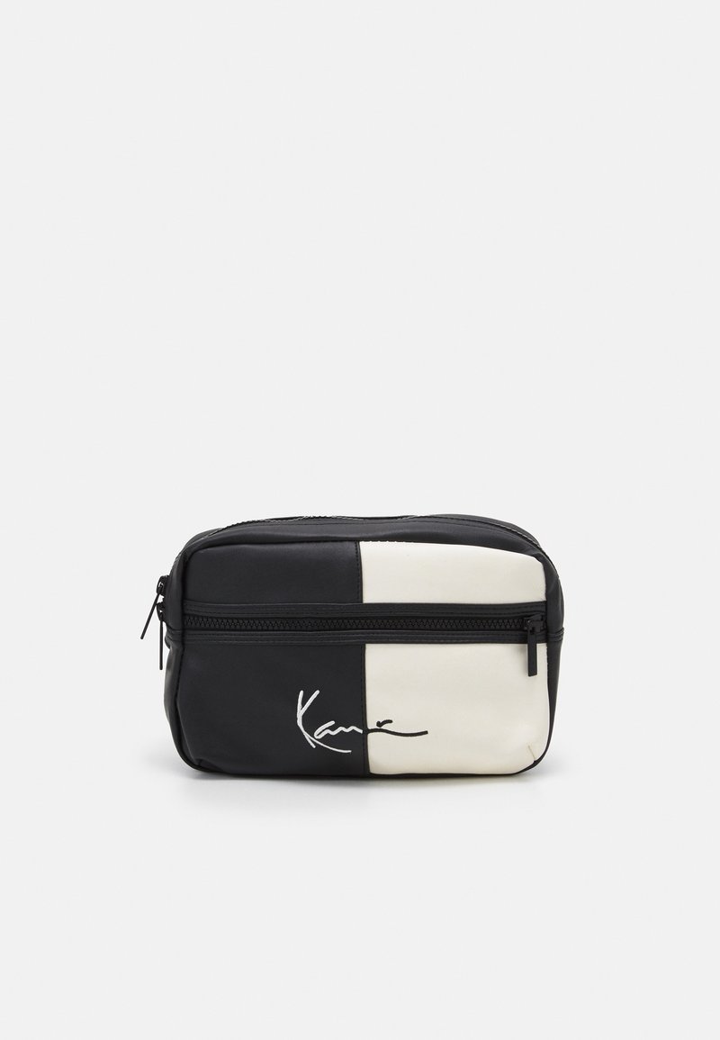 Piccola borsa rettangolare bianca e nera con cerniera frontale e logo in stile firmato ricamato in basso a sinistra.