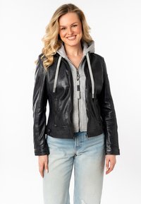 Zwarte leren jas met een aansluitend ontwerp, grijze hoodie eronder, ritssluiting aan de voorkant en geribbelde manchetten, gecombineerd met licht gewaschen jeans.