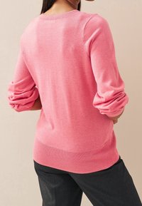 Maglione rosa a maglia con scollatura rotonda, maniche a tre quarti e orlo a coste. Il tessuto appare morbido con una texture liscia.