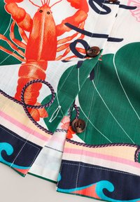 Tissu de chemise avec imprimé homard coloré, feuilles vertes et motif corde, avec boutons marron et détails de couture blanche.