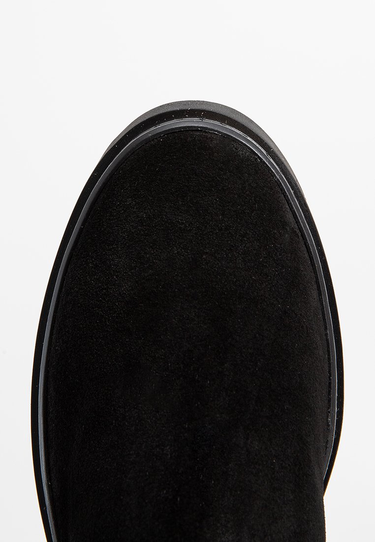 Schwarze Wildleder-Ankle Boots mit einer runden Zehenform, glatter Textur und einer kontrastierenden Gummisohle, die einen subtilen grauen Akzent entlang des Randes aufweist.