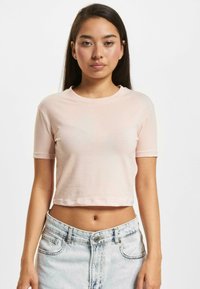 Light pink cropped t-shirt with short sleeves, round neck, and smooth cotton fabric; paired with high-waisted light denim shorts.