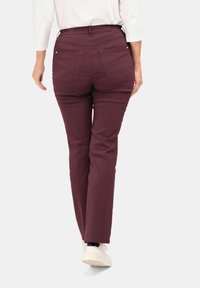 Bordeauxkleurige broek met een recht model, voorzien van een elastische tailleband en twee achterzakken, gecombineerd met witte sneakers.