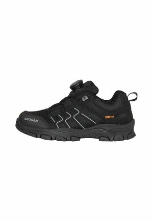 Zapato deportivo negro de corte bajo con suela gruesa, cierre de dial, detalles reflectantes y branding "Skogan" y "Skotex" en el lateral.