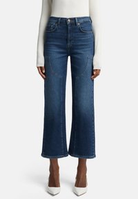 Jeans a vita alta in denim blu scuro, con tasche frontali, dettagli di cucitura doppia e orlo dritto.