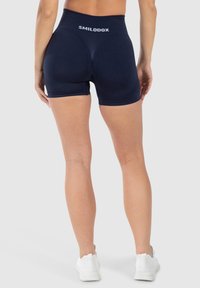 Krátké kalhoty s vysokým pasem v námořnické modré barvě s hladkou strukturou, zdobené bílým logem na pasu a zúženým střihem vhodné pro aktivní nošení.