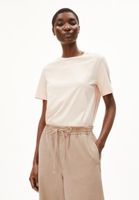 Lichtroze katoenen t-shirt met een ronde hals en korte mouwen, gecombineerd met beige relaxte broek met elastische taille en zakken.