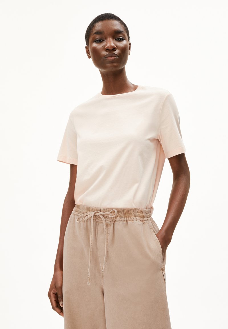 Lichtroze katoenen t-shirt met een ronde hals en korte mouwen, gecombineerd met beige relaxte broek met elastische taille en zakken.