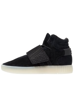 Czarny sneaker typu high-top z teksturowanym paskiem na śródstopiu i półprzezroczystą białą podeszwą, widok z boku na białym tle.