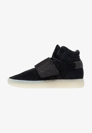 Czarny sneaker typu high-top z teksturowanym paskiem na śródstopiu i półprzezroczystą białą podeszwą, widok z boku na białym tle.