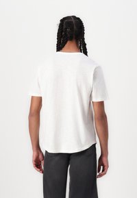 Light gray short-sleeved, relaxed-fit t-shirt with a crew neck and textured fabric. Hemline is slightly curved at the back.