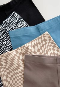 Vier paar leggings: zwarte effen, wit en zwart zebraprint, teal en een beige ruitpatroon met bruine accenten. Van katoenmix stof.
