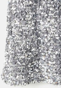 Material argintiu din paiete cu o îmbinare densă de paiete circulare pe un suport moale gri, creând o suprafață texturată strălucitoare.