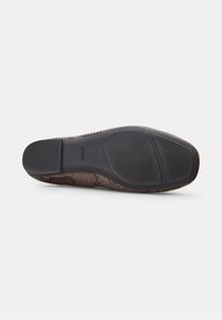 Suela de un zapato de vestir marrón con estampado de serpiente que muestra un tacón negro de goma texturizada y agarres en la parte delantera sobre un fondo blanco.