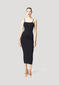 Zwarte mouwloze midi-jurk met een aansluitend ontwerp. Gladde stof textuur en subtiele glans, aangevuld met nude hoge hakken.