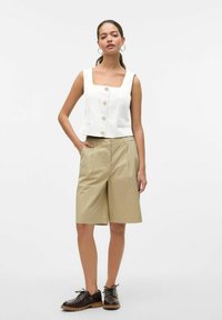Weißes Leinen-Cropped-Top mit quadratischem Ausschnitt und Knöpfen, kombiniert mit beigen knielangen Shorts und braunen Schnürschuhen. Einfaches Design.