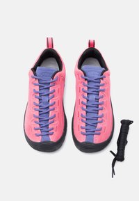 Παντόφλες από ανοιχτό ροζ σουέτ με μωβ κορδόνια, μαύρες λαστιχένιες σόλες και μαύρη εσωτερική επένδυση. Περιλαμβάνει επιπλέον μαύρο κορδόνι.