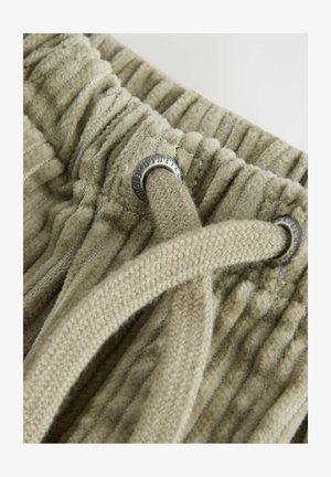 Tekstūrēts, gaiši krēmkrāsas audums ar vertikālām ripām, ar izstrādātu auklu, caur kuru ir iešūta sudraba krāsas acs.