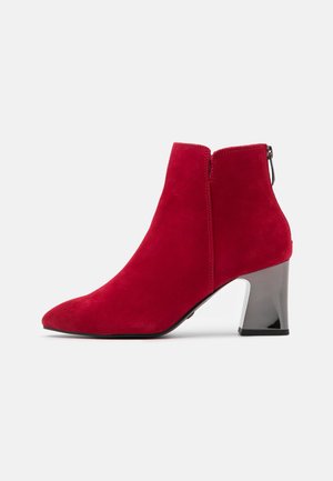 Roter Wildleder-Stiefeletten mit spitzer Zehenpartie und glänzendem silbernem Blockabsatz, seitlichem Reißverschluss und hinterer Zuglasche auf schlichtem hellem Hintergrund.