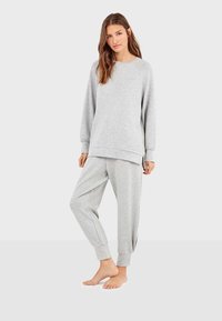 Grijze sweatshirt met een ontspannen pasvorm en lange mouwen, gecombineerd met bijpassende taps toelopende sweatpants met elastische boorden. Gladde textuur.