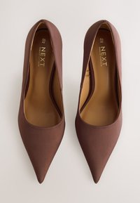 Brune satinspidse pumps med en glat tekstur og en subtil glans, med en lav udskæring foran og en indersål med mærke.