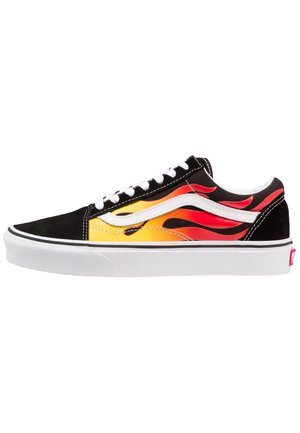 Svart ruskinn sneakers med gule og røde flammegrafikker, hvite detaljer og svarte snørebånd. Har en hvit gummisåle med lett tekstur.