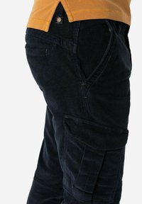Dunkelblaue Corduroy-Cargo-Hosen mit Taschen und strukturiertem Stoff; der Bund hat einen Knopfverschluss und ein Markenlogo-Detail.