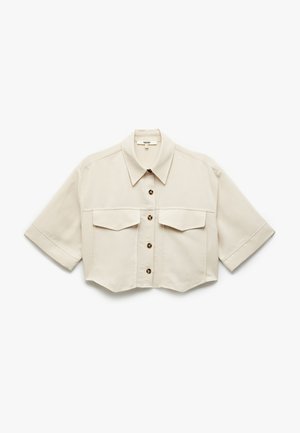 Camisa beige recortada con cuello puntiagudo, mangas cortas, cierre frontal de botones y dos bolsillos en el pecho con botones marrones.