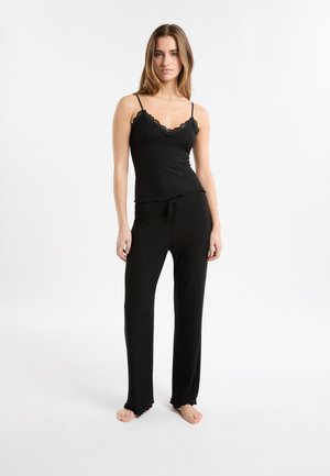 Ensemble de pyjama noir côtelé comprenant un débardeur ajusté avec bordure en dentelle, bretelles réglables et pantalon à coupe ample avec ourlets à volants. Texture de tissu douce.