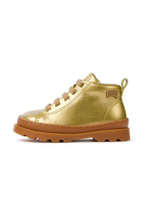 Gold leather ankle boot with brown rubber sole and beige laces, featuring a pull tab and a small branded patch on the heel.
