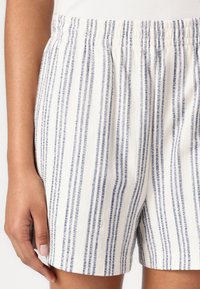 Vevede bomullsshorts med hvit base og vertikale marineblå striper, med elastisk midjebånd og avslappet passform.