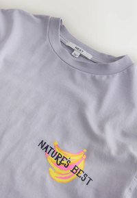 Light purple t-shirt with a graphic of three yellow bananas and the text "NATURE'S BEST" on the chest.