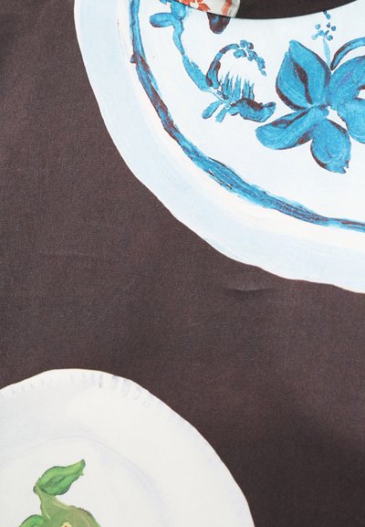 Δύο λευκά κεραμικά πιάτα με μπλε ανθικά και πουλιών σχέδια σε σκοτεινό καφέ υφασμάτινο φόντο.