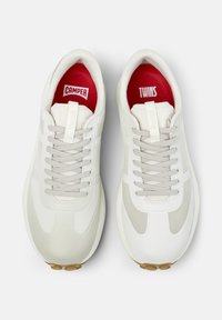 Sneakers bianchi con accenti grigio chiaro e suole beige, dotati di etichette interne rosse che riportano la scritta "CAMPER" e "TWINS."
