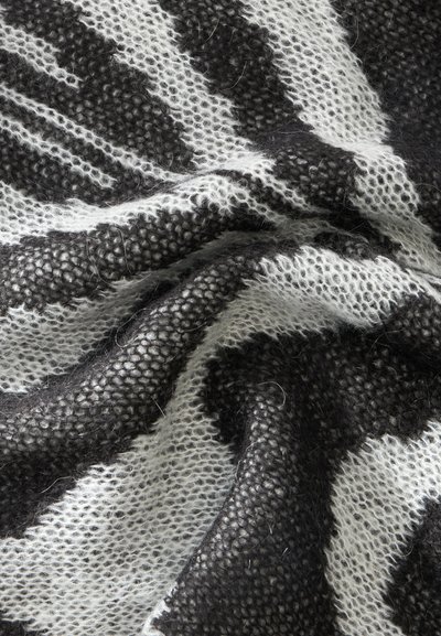 Tissu tricoté doux avec motif rayé noir et blanc, montré en gros plan avec texture visible et plis légers.