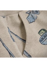Beige katoen stof met verschillende blauwe en groene illustraties van machines. Close-up die textuur en stikdetails toont.