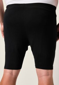 Shorts neri elasticizzati con una trama liscia, che arrivano a metà coscia, caratterizzati da una semplice vita elastica senza decorazioni.